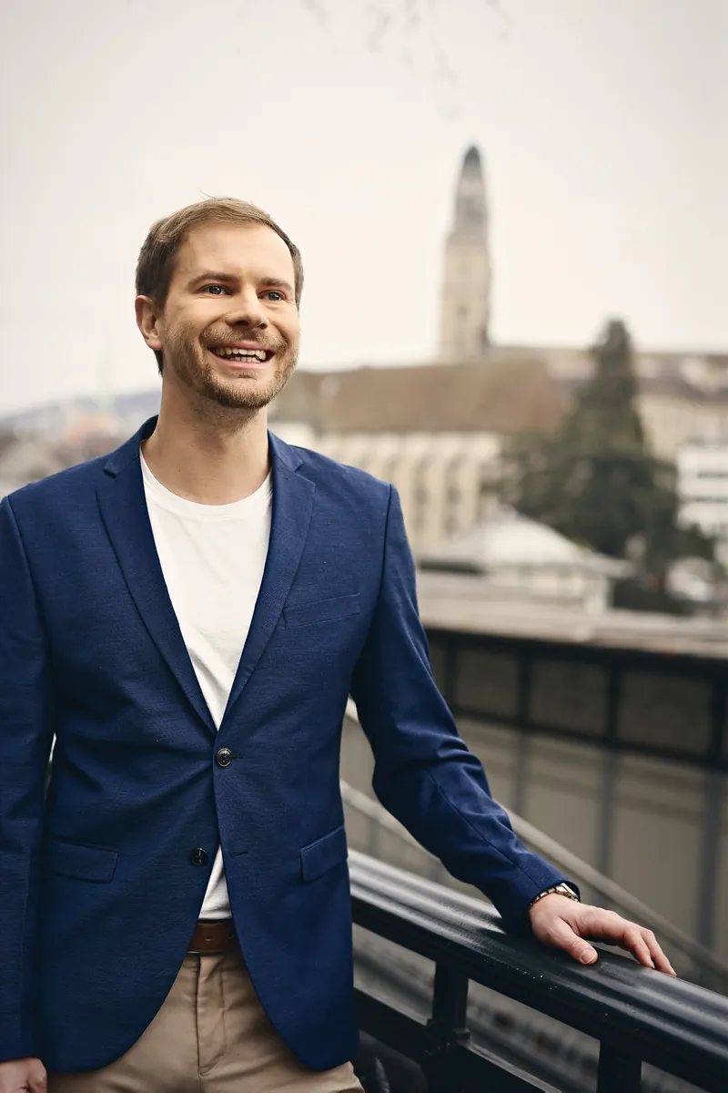 Lukas Bärlocher im Blazer an der Limmat, im Hintergrund das Grossmünster